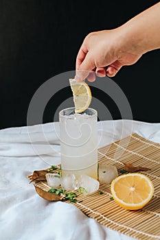 Hand drop fresh slice lemon on refreshing drink or beverage homemade ice lemonade juice soda cocktail