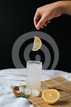 Hand drop fresh slice lemon on refreshing drink or beverage homemade ice lemonade juice soda cocktail
