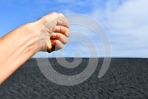 Hand dropping black sand