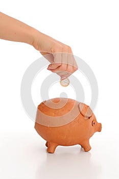 Hand dropping coin in piggy bank photo