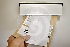 A hand drops an envelope and a parcel into a mailbox,