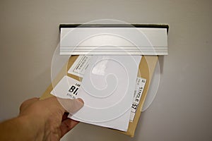 A hand drops an envelope and a parcel into a mailbox,