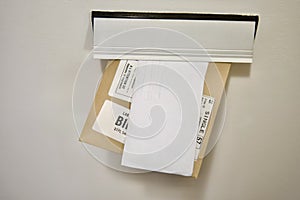 A hand drops an envelope and a parcel into a mailbox,