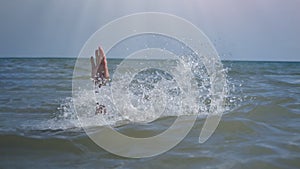 The hand of a drowning man sticking out of the water is covered in splashes