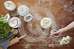 Hand dusting dough with flour wooden kitchen surface