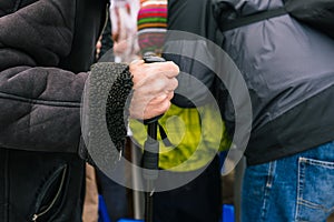 The hand of an elderly man with a cane. An old man leans on a stick. Beggar pedestrian on the street. The old man`s hand is old.