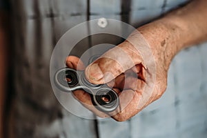 The hand of an elderly man holds Fidget Spinner