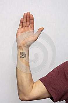 The hand of an elderly man with a tattooed QR code on a light background. Concept: assigning QR codes to people with antibodies to photo