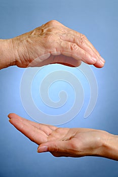 Hand of elderly woman above young woman's hand