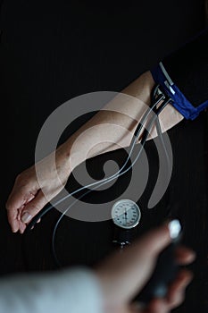 A hand of an elderly woman being checked by a doctor with tonometer