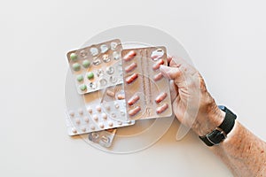 Hand of elderly woman holding pills and medicine, white background