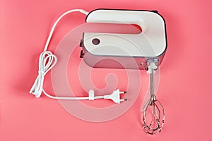 Hand electric blender with whisks on a red background, close-up