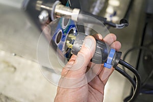 Hand of electrician inserts plug into socket