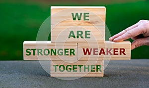 Hand exchanges a wooden brick and changes the expression `we are weaker together` to `we are stronger together`.