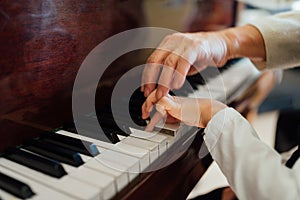 Hand of an experienced pianist helping young students