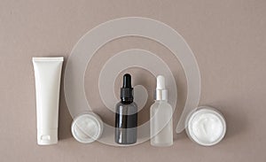 Hand, eye and facial moisturizer cream and serum and essential in glass bottles on beige background. Set for skin and body care