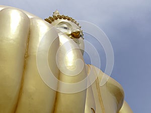 Hand and face of big golden buddha statue