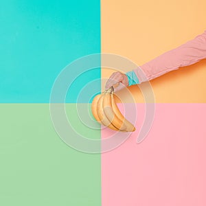 Hand in fashionable clothes holding Bananas. Vanilla summer style Minimal creative art