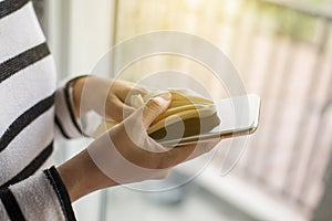 Hand female cleaning her mobilephone on screen with microfiber