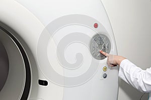 A hand of female doctor pushing control button on CT scanner