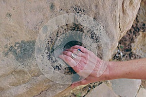 Hand of female hiker with beautiful silver rings grips rock while hiking in New Mexico