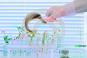 hand of female laboratory assistant, scientist trichologist processes hair sample, curls with plant extracts, concept science,