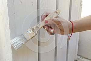 Hand of a female painting and reforming a wooden fence