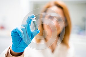 Hand of female scientist in rubber glove shaking test tube