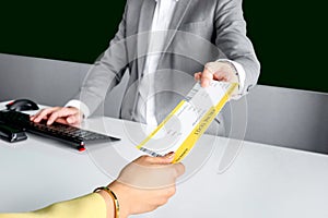 Hand of female traveler giving boarding pass to passenger service agent staff for checking information at check in area airport