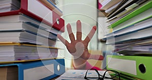 Hand of female worker appears between stacks of folders