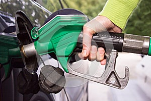 Hand filling the car tank with gasoline