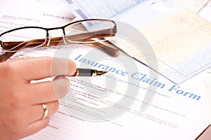 Hand filling in insurance claim form photo