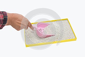 A hand filtering artificial sand with plastic shovel for cat