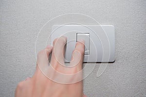 Hand with finger on light switch turn on turn off lights.