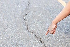 Hand finger pointing inspect cracked asphalt road street highway countryside