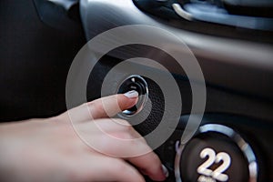 hand finger presses the start stop button in a modern car. close-up. no face. selective focus