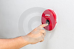 Hand with finger pressing red fire alarm on the wall