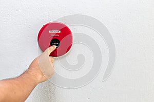 Hand with finger pressing red fire alarm on the wall