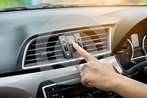 Hand or finger woman driver press car emergency light botton on dashboard