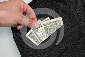 A hand fingering a dollar bill from his pocket. Dollar bills sticking out of your pocket