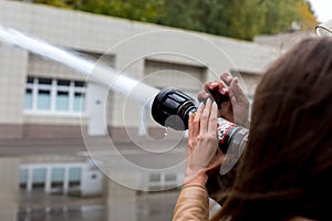 Hand with fire fighting nozzle. Water jet splashing from a fire fighting firehose nozzle