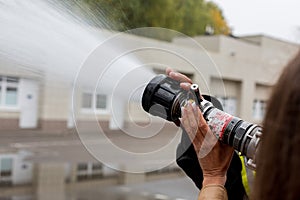 Hand with fire fighting nozzle. Water jet splashing from a fire fighting firehose nozzle