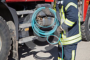 Hand of a fireman connecting a firehose to an outlet.