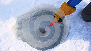 Hand Of The Fisherman Cleans The Scoop Hole From The Ice For Winter Fishing