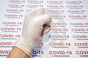 Hand fist in white medical glove against covid-19 background.