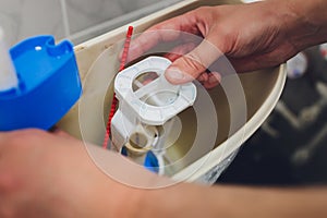 Hand is fixing a toilet cistern at home.