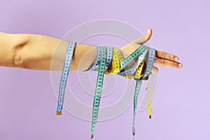 Hand with flexible rulers on light purple background