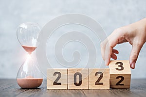Hand flip block 2022 to 2023 text with hourglass on table. Resolution, time, plan, goal, motivation, reboot, countdown  and New