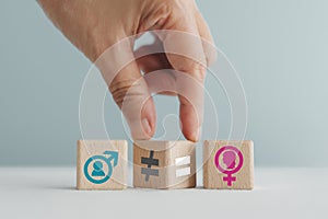 hand flip unequal to equal sign on wooden cubes between male and female sign. Equality of gender, employment opportunity