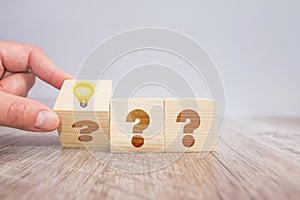 Hand flip wooden cube block with question mark symbol and light bulb icon